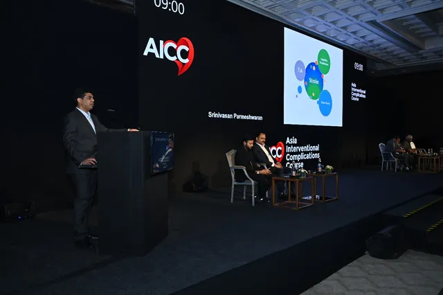 A speaker at the podium beside the presentation screen